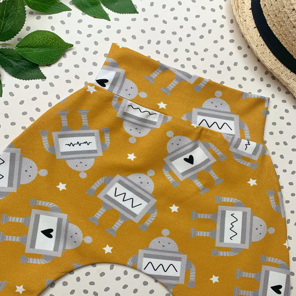 flat lay of yellow haremt pants featuring grey robots, some with a heart on their chest