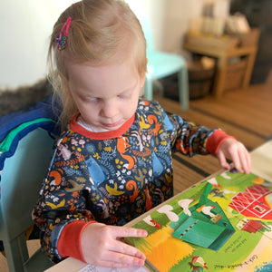 child reading a book in a forest animal sweatshirt featuring bears. foxes, squirrels